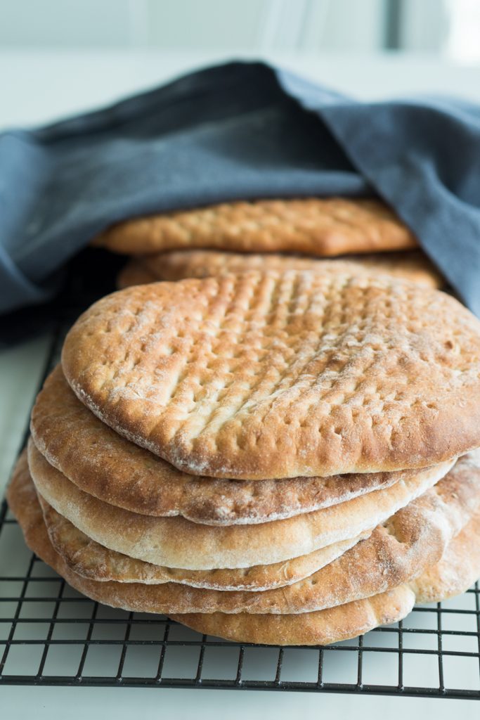 Kuvassa on kauniisti paistettuja Hönökaka-leipiä, jotka on aseteltu näyttävästi ritilälle jäähtymään. Leipä on litteä, pehmeä ja vaalea, ja sen pinnalla voi nähdä kauniita kullanruskeita kohtia, jotka kertovat täydellisestä paistosta. Hönökakat on valmistettu perinteisistä raaka-aineista, ja ne tarjoavat herkullista makua sekä monipuolisuutta ruoanlaitossa.